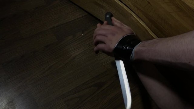 Man trying to use a large knife to break black taped wrists