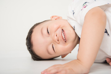 Obraz na płótnie Canvas Happy boy toddler lay down on the floor with smile face on white