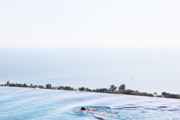 Panorana view of edgeless swimming pool with open view of beautiful ocean in summer.