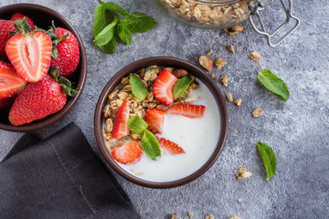 Breakfast with yogurt, granola of muesli and strawberries on gray concrete table background. Healthy Vegan Clean Diet Food Concept. Top view, copy space, flat lay