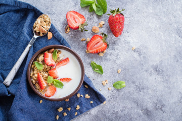 Food Background. Breakfast with yogurt, granola of muesli and strawberries on gray concrete table background. Healthy Diet Food Concept. Top view, copy space, flat lay