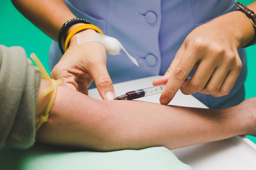 The nurse takes the patient's blood with a syringe.