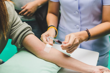 The nurse takes the patient's blood with a syringe.