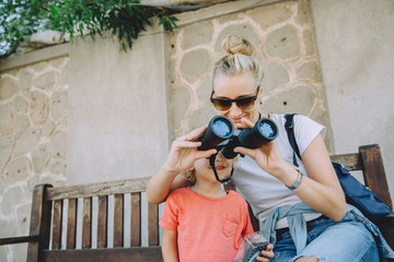 Young woman with her cute little son sightseeing with binoculars in Dubai, UAE
