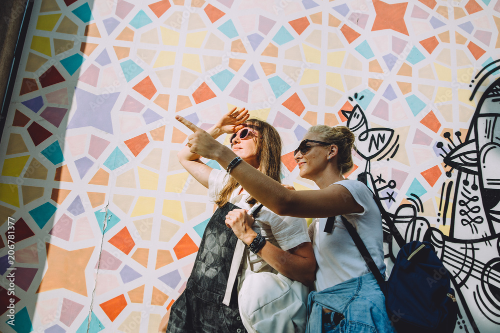 Wall mural Two young happy women against bright wall in Dubai, UAE