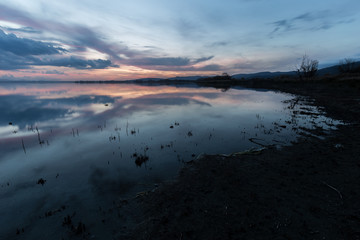 Lake shore at sunset, with perfect reflections of some red and o