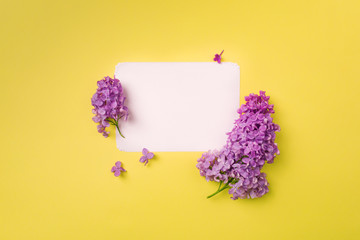 Postcard with fresh splendid lilac flowers and empty tag for your text on yellow background.