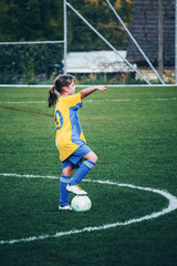 Young girl playing football at stadium with local girls football team and showing where to stand. Small city stadium located in Switzerland.