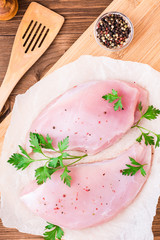 Raw turkey fillet in spices and herbs on a cutting board on a wooden table. Top view