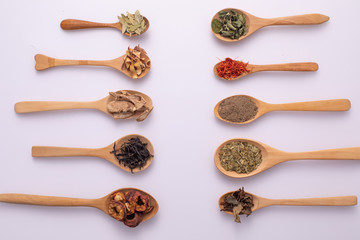Various kind of dried leaves, fruit and flower put in many kind of wooden spoons on white background.