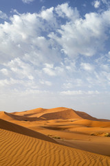 Fototapeta na wymiar orange dunes and clouds in sunset time in Sahara desert in Morocco