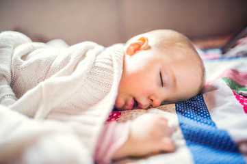 A toddler girl sleeping on a bed at home.