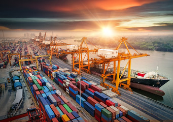 Logistics and transportation of Container Cargo ship and Cargo plane with working crane bridge in shipyard at sunrise, logistic import export and transport industry background