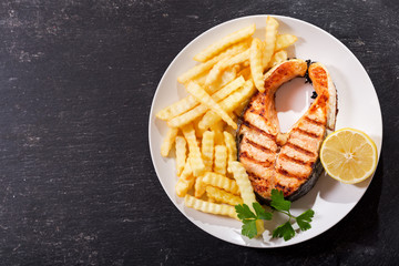 plate of grilled salmon steak with french fries, top view