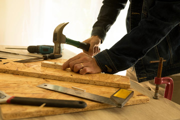 Close up of hammering a nail into wooden board.