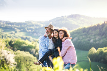 Senior couple with grandaughter outside in spring nature, relaxing and having fun.