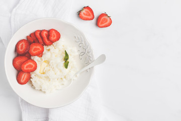 Rice milk porridge with strawberry and butter for breakfast. White background, top view, copy space.