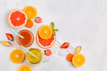 Multicolored fruit juices or smoothie in glass jars and ingredients. Top view, isolated on white background.