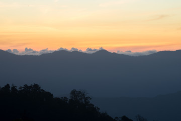 Mountain silhouette, the clouds at sunrise, warm yellow sunlight, sunset and sunrise, view from the top view of mountains.