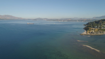Aerial view: Cargo, Reefer ship in the sea bay. Subic Bay, Philippines, Luzon. Cargo ship in the harbor, against the backdrop of the mountains.