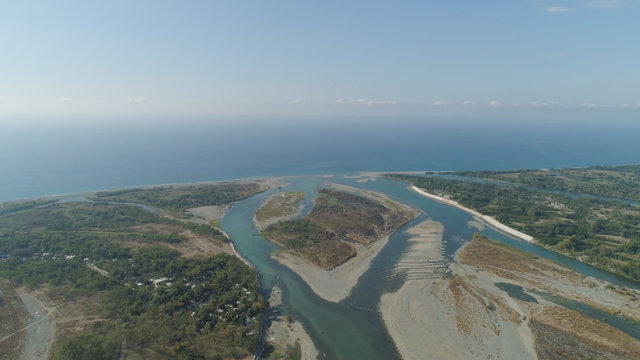 Aerial view of rver flowing into the sea in Philippines,Luzon. ropical landscape with sandy coast and river among farmer fields flowing into the blue ocean