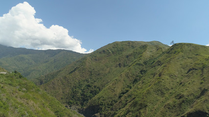 Fototapeta premium Aerial view of mountains covered forest, trees against the sky and clouds.Cordillera region. Luzon, Philippines. Mountainous tropical landscape.