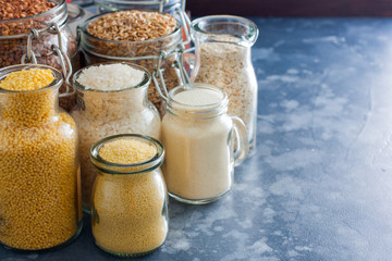 Various cereals in glass jars - rice, millet, oatmeal, couscous, buckwheat, semolina, copy space