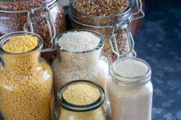 Various cereals in glass jars on a table, horizontal