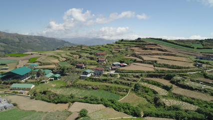 Aerial view of rice terraces and agricultural farm land on the slopes of mountains valley. Cultivation of agricultural products in mountain province. Mountains covered forest, trees. Cordillera region