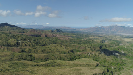 Obraz premium Aerial view of mountains covered with green vegetation, valley, trees in vicinity volcano Pinatubo. Slopes of mountains, sky and clouds. Cordillera region. Luzon, Philippines.