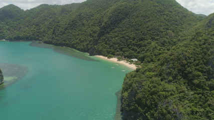 Aerial view coastline with beach and mountains covered with tropical forest in province Caramoan, Philippines. Landscape with sea, mountains and beach.
