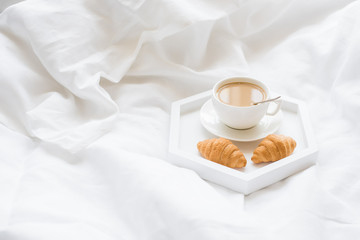 Early morning breakfast in bed, coffee and croissant on the tray
