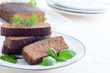 Sliced pate-casserole from chicken liver on a white plate with fresh green, horizontal, copy space for text