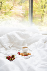 Fototapeta na wymiar Early morning breakfast in bed, coffee and croissant with strawb