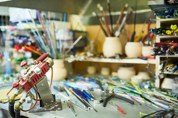 Empty workstation in glass working studio with gas torch in foreground, copy space
