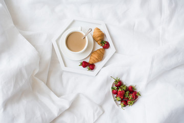 Fototapeta na wymiar Early morning breakfast in bed, coffee and croissant with strawb