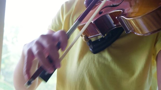 Young asian boy playing violin in classroom
