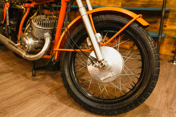 Vintage orange motorcycle detail. Spoke wheel and engine.