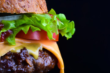 Cheese burger with grilled meat, cheese, tomato, salad and onion rings. Close-up of delicious fresh...