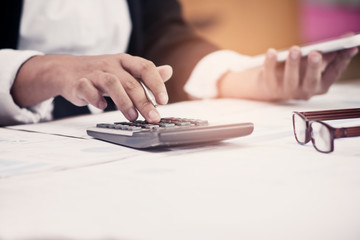 Fototapeta premium A business man using calculator for calculate expenses bills in his workplace. Business concept.