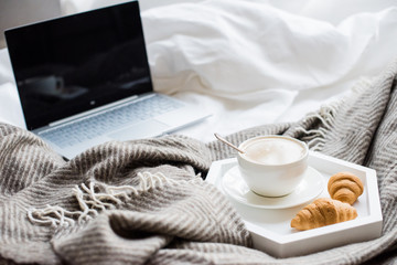 Cozy weekend at home, laptop and coffee in bed