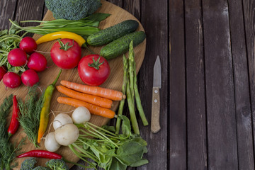 on a wooden table vegetables asparagus, broccoli, chili, tomato, radish, carrots and dill - background of vegetables