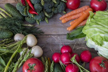 on a wooden table vegetables asparagus, broccoli, chili, tomato, radish, carrots and dill - background of vegetables