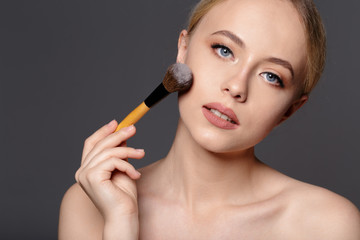 Obraz premium Beauty portrait of a smiling beautiful half naked woman posing with make-up brushes