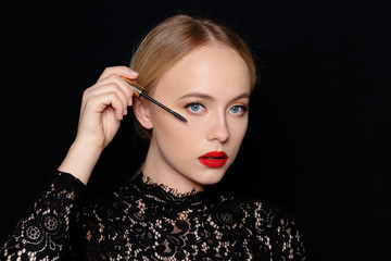 Beauty portrait of a smiling beautiful half naked woman posing with make-up brushes