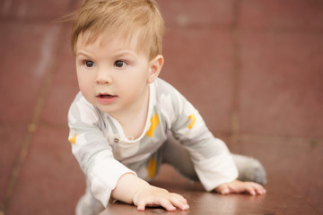 Concept: family values. Portrait of adorable innocent funny brown-eyed baby playing at outdoor playground.