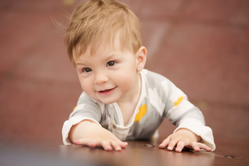 Naklejka premium Concept: family values. Portrait of adorable innocent funny brown-eyed baby playing at outdoor playground.