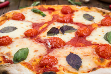 rustic italian pizza Margarita with mozzarella, cherry tomatoes and basil leaves on wooden background