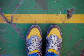 Legs in yellow sneakers at the yellow line
