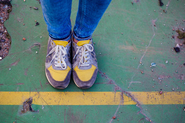 Legs in yellow sneakers at the yellow line
